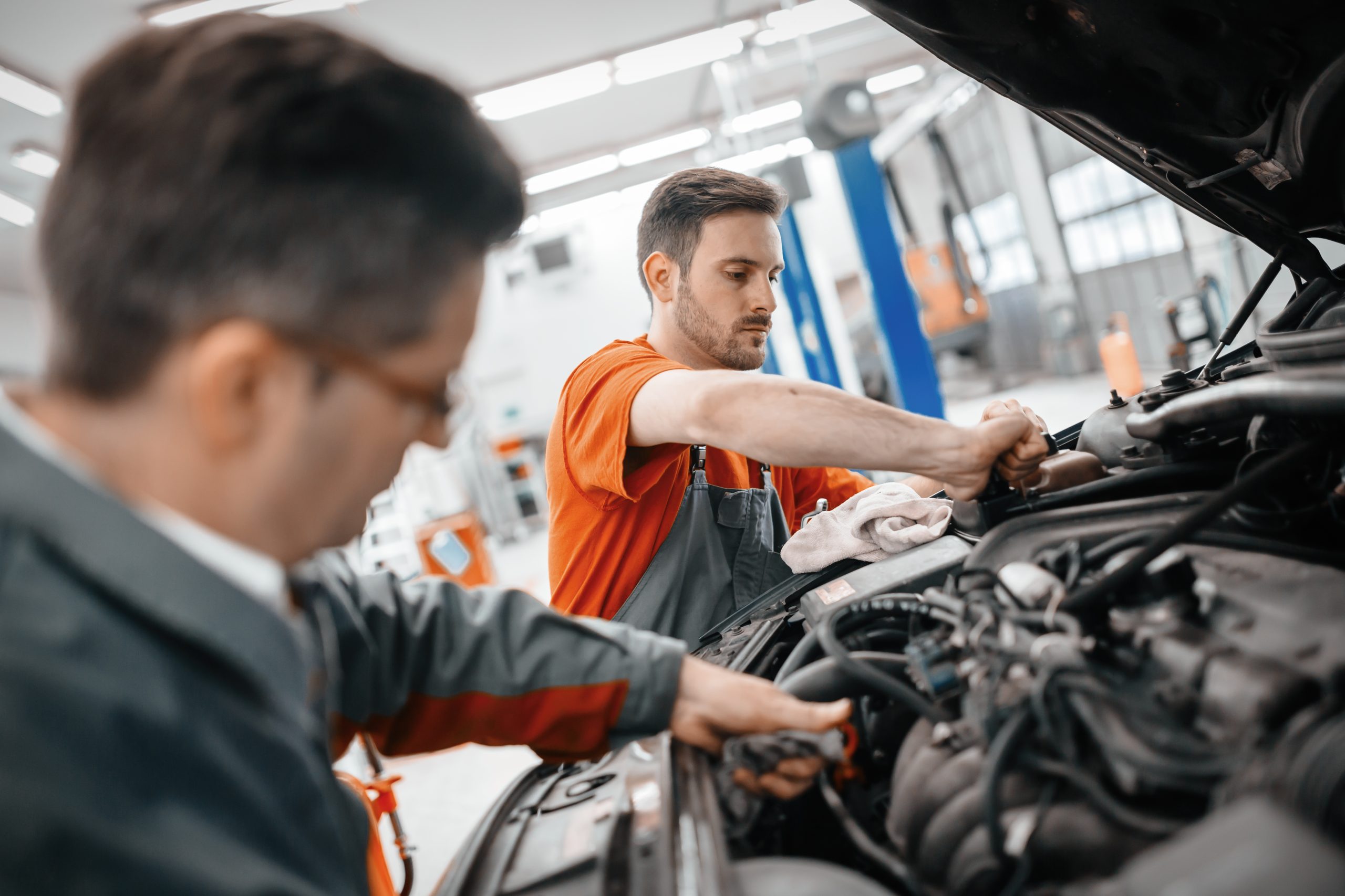 Mechanics working on a car engine in an auto repair shop.
