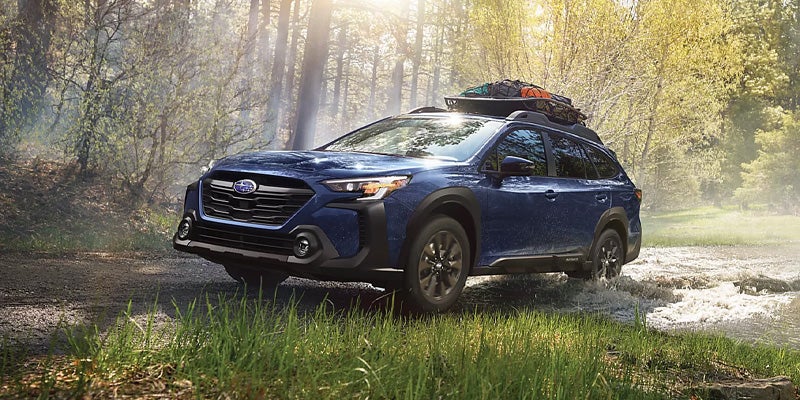 Blue Subaru SUV driving through a forest stream
