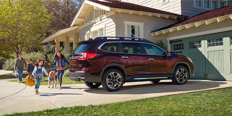 Maroon SUV parked at a suburban house with family