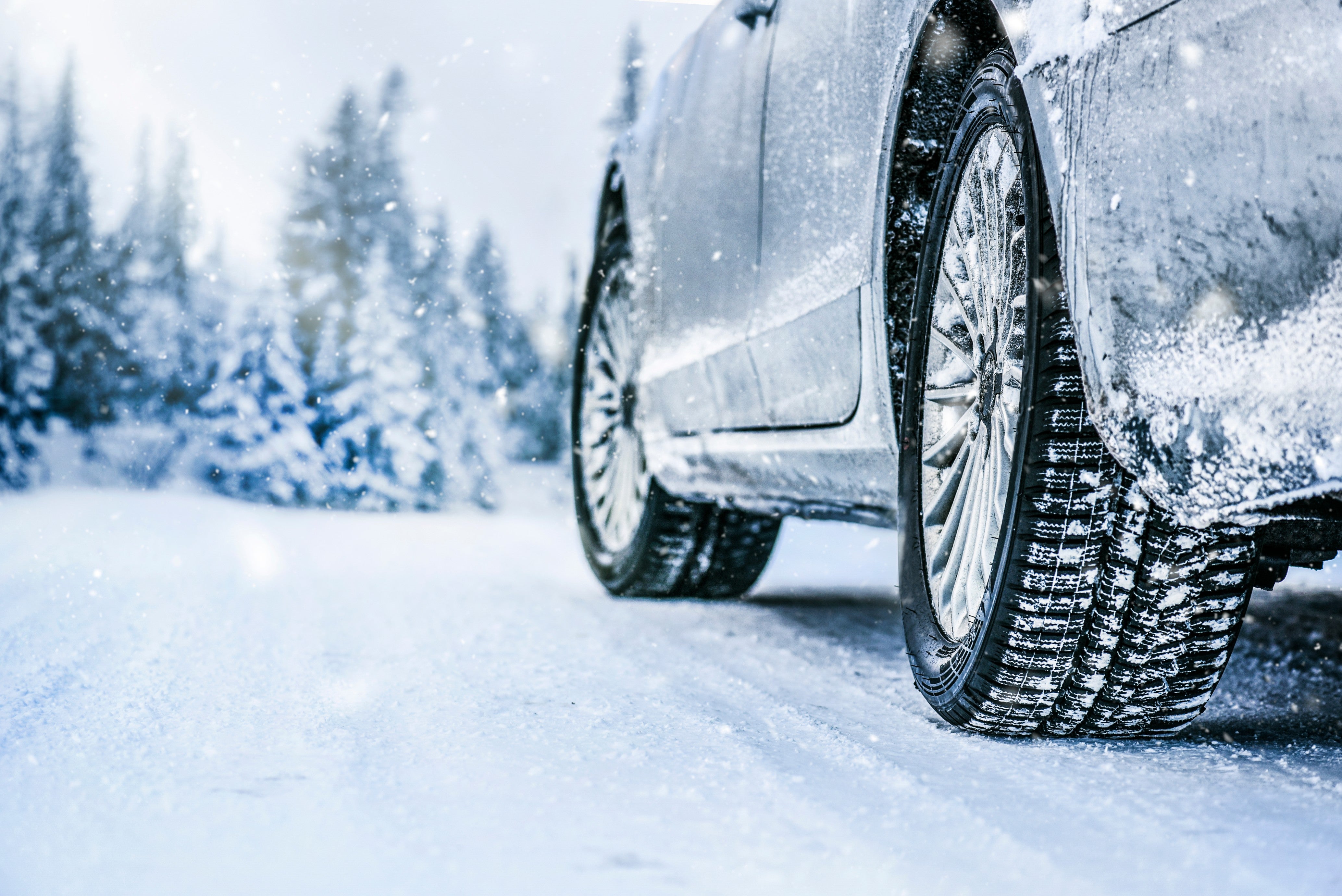 Car tires driving through snowy winter road.